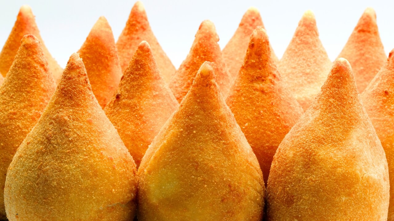 Várias coxinhas empanadas pefeitamente com o fundo branco.